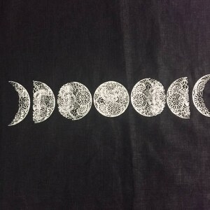 May include: Black fabric with a white moon phase design. The moon phases are in a crescent shape and have a detailed, intricate design.