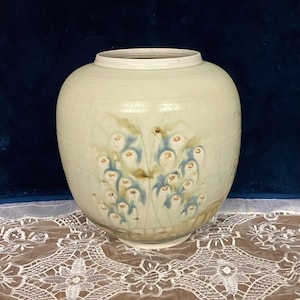 May include: A ceramic vase with a light green glaze and a floral design in shades of blue and brown.
