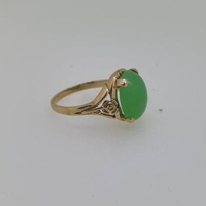 May include: A gold ring with a green oval gemstone set in a floral design.