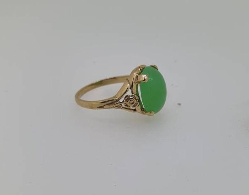 May include: A gold ring with a green oval gemstone set in a floral design.