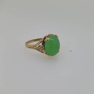 May include: A gold ring with a green oval gemstone set in a delicate floral design.