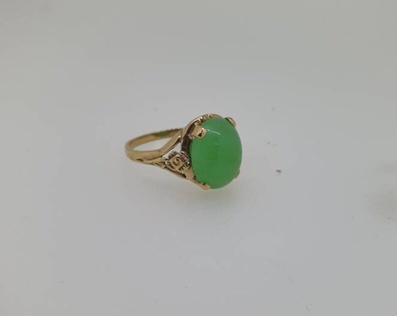 May include: A gold ring with a green oval gemstone set in a delicate floral design.