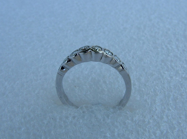 May include: A silver band ring with a row of small, clear round stones set in the band.