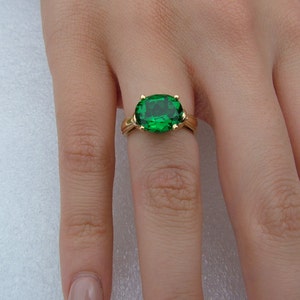 Puede incluir: Un anillo de oro con una gran piedra preciosa verde de forma ovalada.