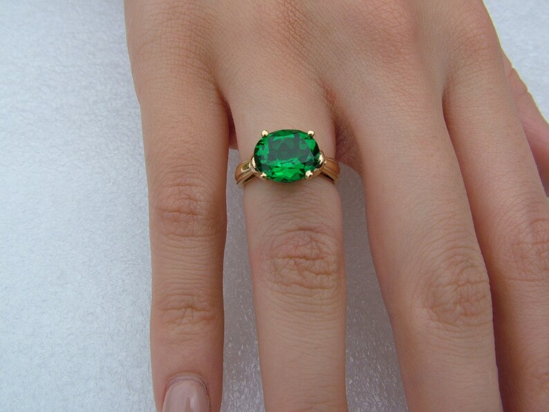Puede incluir: Un anillo de oro con una gran piedra preciosa verde de forma ovalada.
