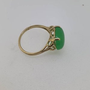 May include: A gold ring with a green oval gemstone set in a delicate filigree design.