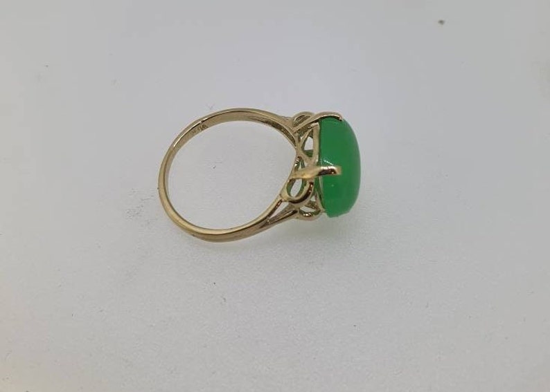 May include: A gold ring with a green oval gemstone set in a delicate filigree design.