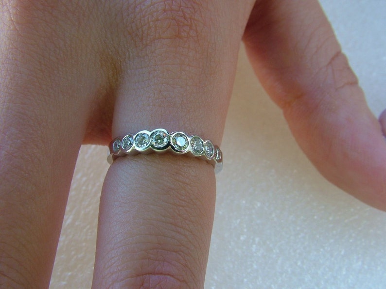 May include: A silver band ring with a row of round, clear gemstones.