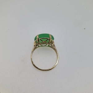 May include: A gold ring with a large, green gemstone set in a delicate, intricate design.