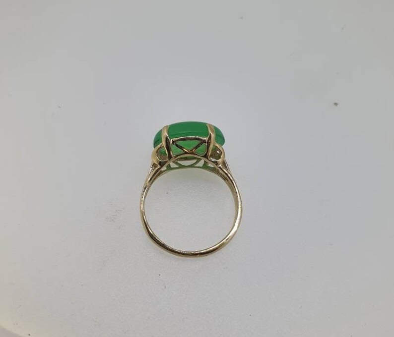 May include: A gold ring with a large, green gemstone set in a delicate, intricate design.