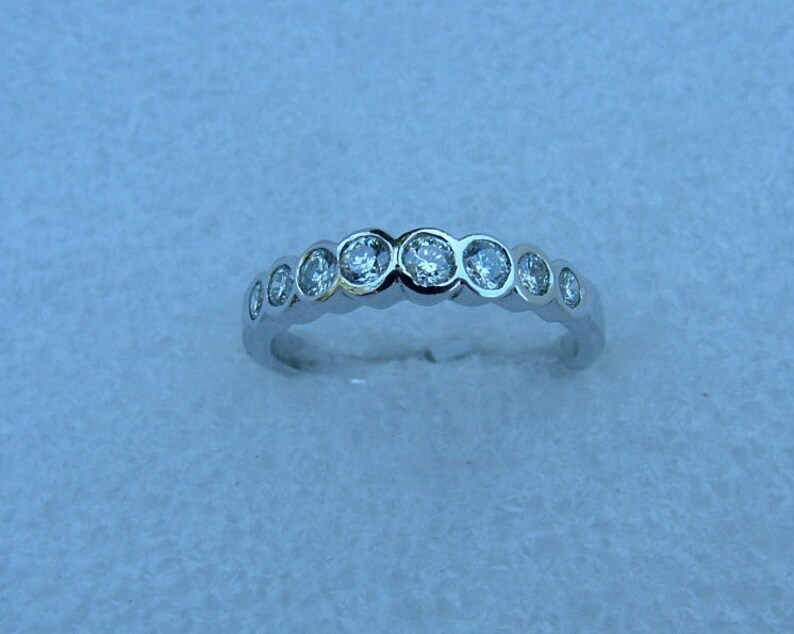 May include: A silver band ring with a row of round, clear gemstones.