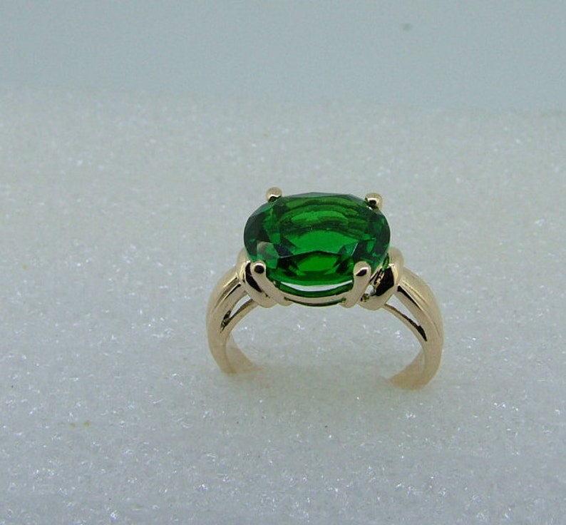 Puede incluir: Un anillo de oro con una gran piedra preciosa verde de forma ovalada.
