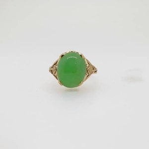 May include: A gold ring with a green oval gemstone set in a floral design.