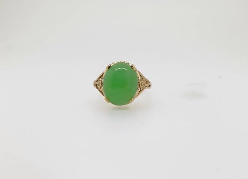 May include: A gold ring with a green oval gemstone set in a floral design.
