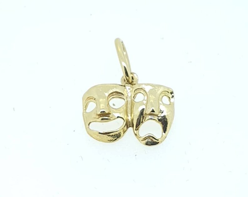 May include: Gold charm pendant featuring two theater masks, one smiling and one frowning.
