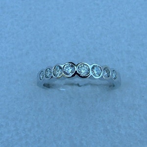 May include: A silver band ring with a row of clear round gemstones.