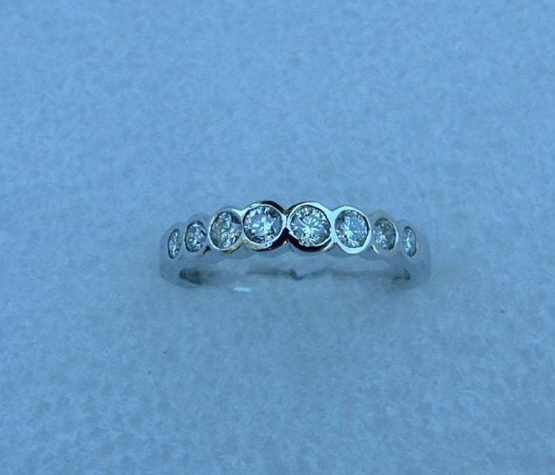 May include: A silver band ring with a row of clear round gemstones.