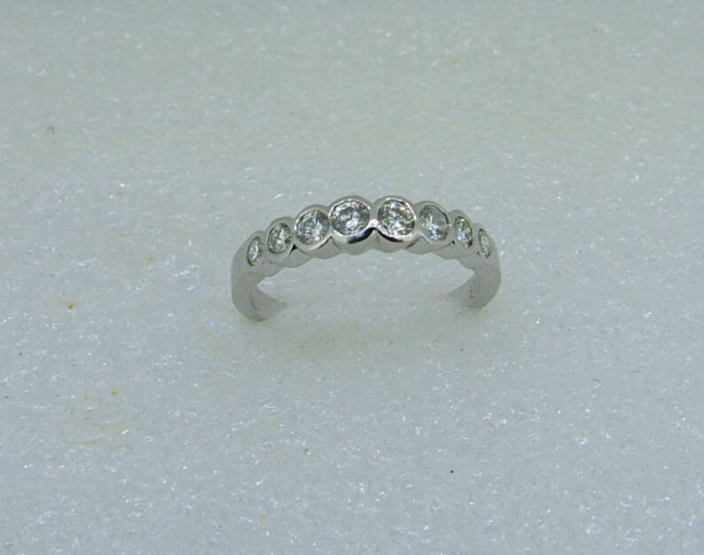 May include: A silver band ring with a row of small round clear stones.
