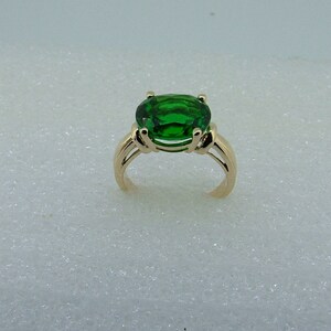 Puede incluir: Un anillo de oro con una gran piedra preciosa verde de forma ovalada.