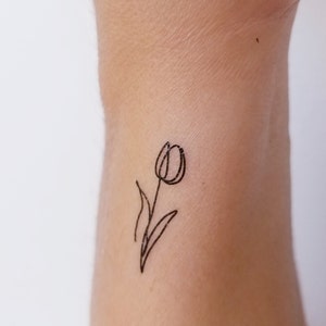 May include: A simple black line drawing of a tulip flower on a person's wrist.