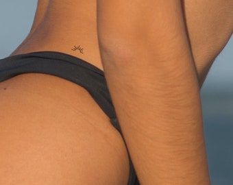 May include: A small sun tattoo on a person's lower back.