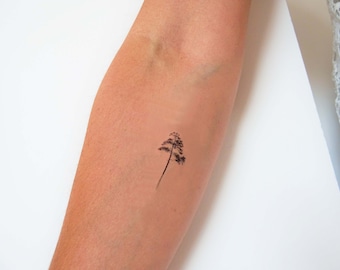 May include: A simple black temporary tattoo of a small tree on a person's arm.