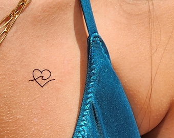 May include: A small, simple tattoo of a heart with a wave inside, on a person's shoulder.