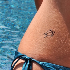 May include: A simple line drawing of a turtle is tattooed on a person's hip.