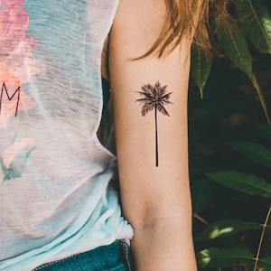 May include: A black and white temporary tattoo of a palm tree on a person's arm.