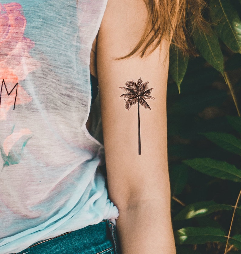 May include: A black and white temporary tattoo of a palm tree on a person's arm.