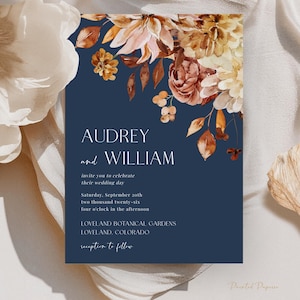 May include: A navy blue wedding invitation with floral watercolor accents. The invitation features the names "Audrey and William" and event details. The floral arrangement includes shades of brown, orange, and cream.