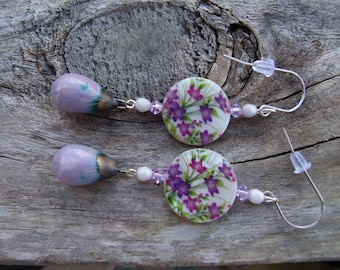 Pendientes largos únicos de flores lila, moradas, blancas y plateadas. Pendientes bohemios de cerámica, conchas y Swarovski. Un regalo hecho a mano para ella.