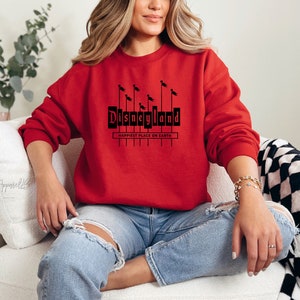 May include: A red sweatshirt with a black graphic of the Disneyland sign with the text "Happiest Place on Earth".