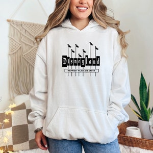 May include: White hooded sweatshirt with a black graphic of the Disneyland sign with the text "Happiest Place on Earth".
