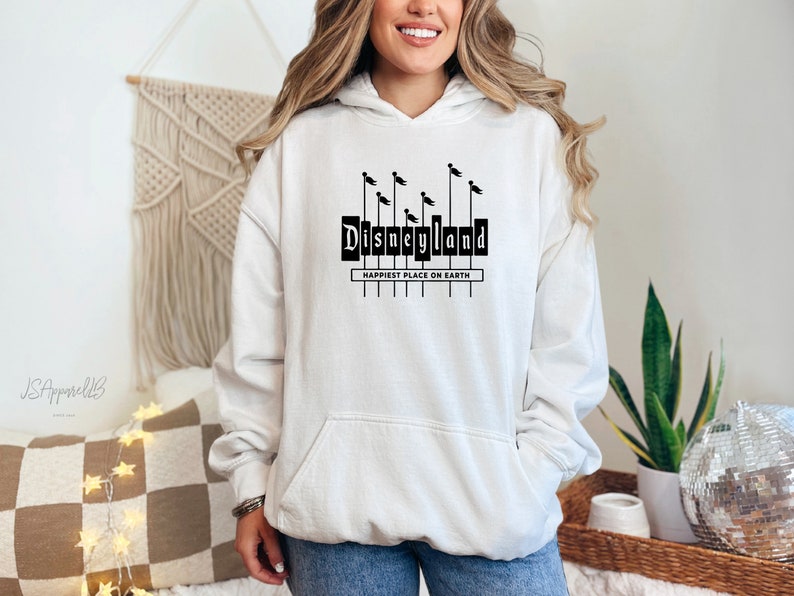 May include: White hooded sweatshirt with a black graphic of the Disneyland sign with the text "Happiest Place on Earth".
