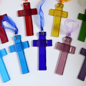 May include: Nine glass crosses in various colours, including red, yellow, green, blue, turquoise, purple, and lavender, with a ribbon attached to each.