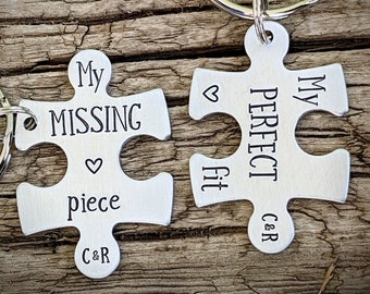May include: Two silver puzzle piece keychains with the text "My Missing Piece" and "My Perfect Fit" on them. The keychains are attached to silver key rings.