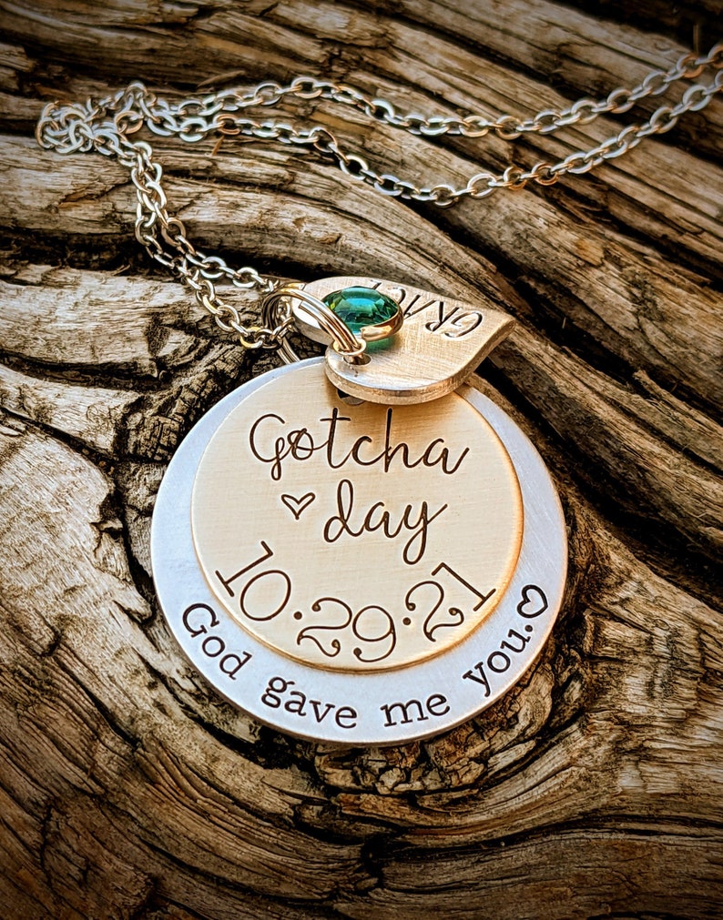 May include: Silver necklace with a gold pendant that says "Gotcha day 10.29.21" and "God gave me you." The pendant has a small green gem.