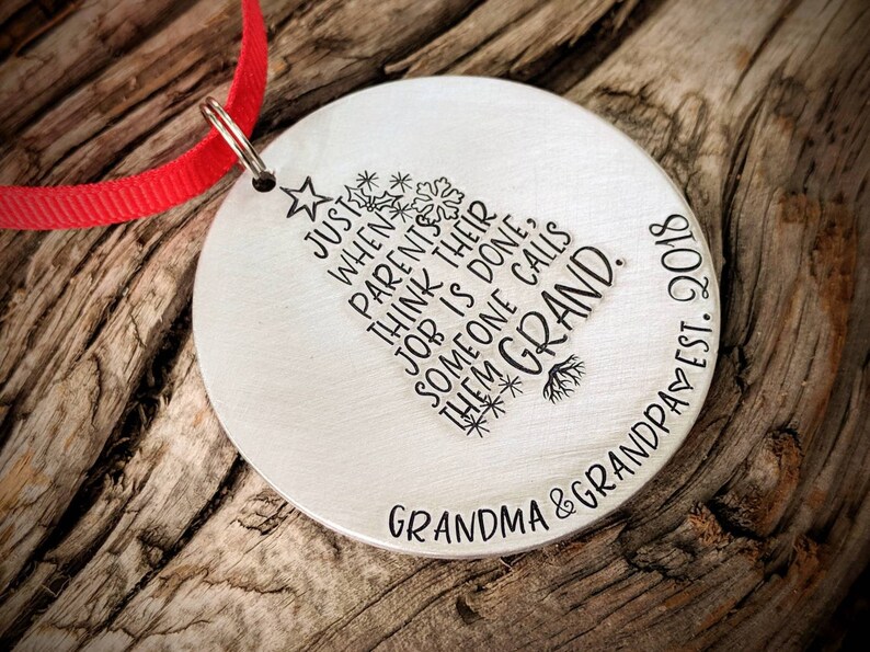 May include: A silver Christmas ornament with a tree design and the text "Just when parents think their job is done, someone calls them Grand."  The ornament also includes the text "Grandma & Grandpa Est. 2010".