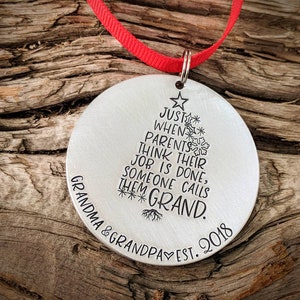 May include: Silver Christmas ornament shaped like a Christmas tree with the text "Just when parents think their job is done, someone calls them Grand." and "Grandma & Grandpa Est. 2018" at the bottom.