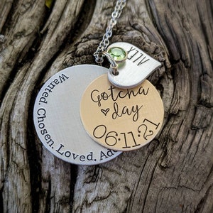 May include: A silver necklace with a silver and gold charm that says "Gotcha day 06:11:21" and a smaller silver charm that says "ALEX".