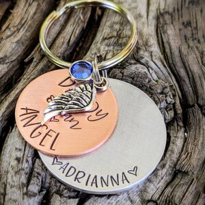 May include: Copper and silver keychain with a blue rhinestone, a small silver wing charm, and the text "My Angel is in Heaven" and "Adrianna" on the bottom.