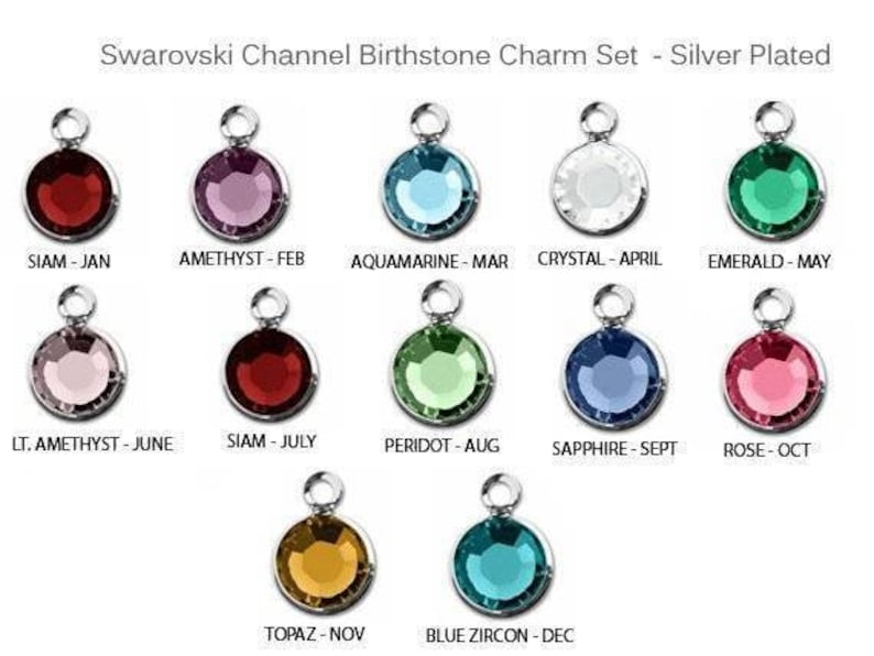 May include: A set of 12 silver-plated charms featuring Swarovski crystals in various colors, representing the birthstones for each month of the year. The charms are labeled with the month and birthstone name.