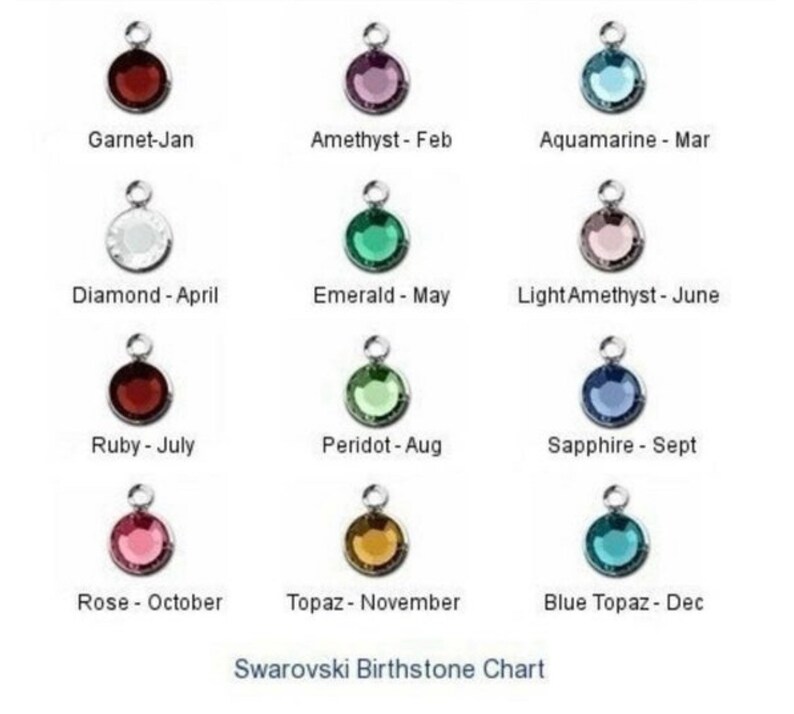 May include: A chart showing the Swarovski birthstones for each month of the year. The chart features a small, round crystal charm for each month, with the name of the stone and month listed below each charm.