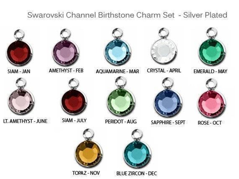 May include: A set of 12 silver-plated charms featuring Swarovski crystals in various colors, representing the birthstones for each month of the year. The charms are labeled with the month and birthstone name.
