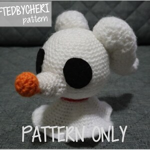 May include: White crocheted amigurumi ghost with black eyes and an orange nose. The ghost is wearing a red ribbon around its neck. The text "a CRAFTEDBYCHERI pattern" is in the top left corner of the image. The text "PATTERN ONLY" is in the bottom center of the image.