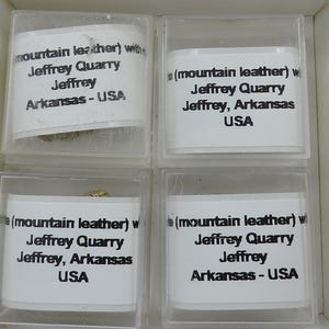 May include: Four small clear plastic boxes with white labels. Each box contains a small piece of rock and a label that reads "(mountain leather) with Jeffrey Quarry Jeffrey, Arkansas USA".