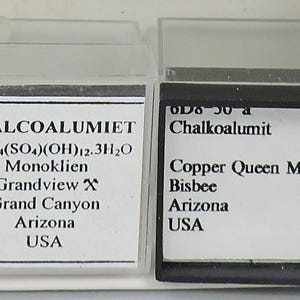 May include: Two mineral samples in clear plastic cases. The left case has a label that reads "CHALCOALUMIET" and other scientific information. The right case has a label that reads "Chalkoalumit" and "Copper Queen Mine, Bisbee, Arizona, USA."