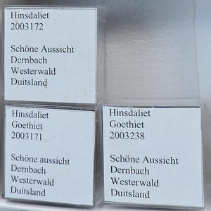 May include: Three small, clear plastic cases each containing a white label with black text. The labels include the words "Hinsdaliet", "Goethiet", and "Schöne Aussicht", along with other details.