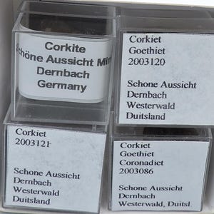 Puede incluir: Cuatro pequeños recipientes de plástico transparente con etiquetas blancas. Las etiquetas contienen las palabras "Corkite", "Goethiet", "Schone Aussicht", "Dernbach", "Westerwald" y "Germany". Las etiquetas también tienen números.